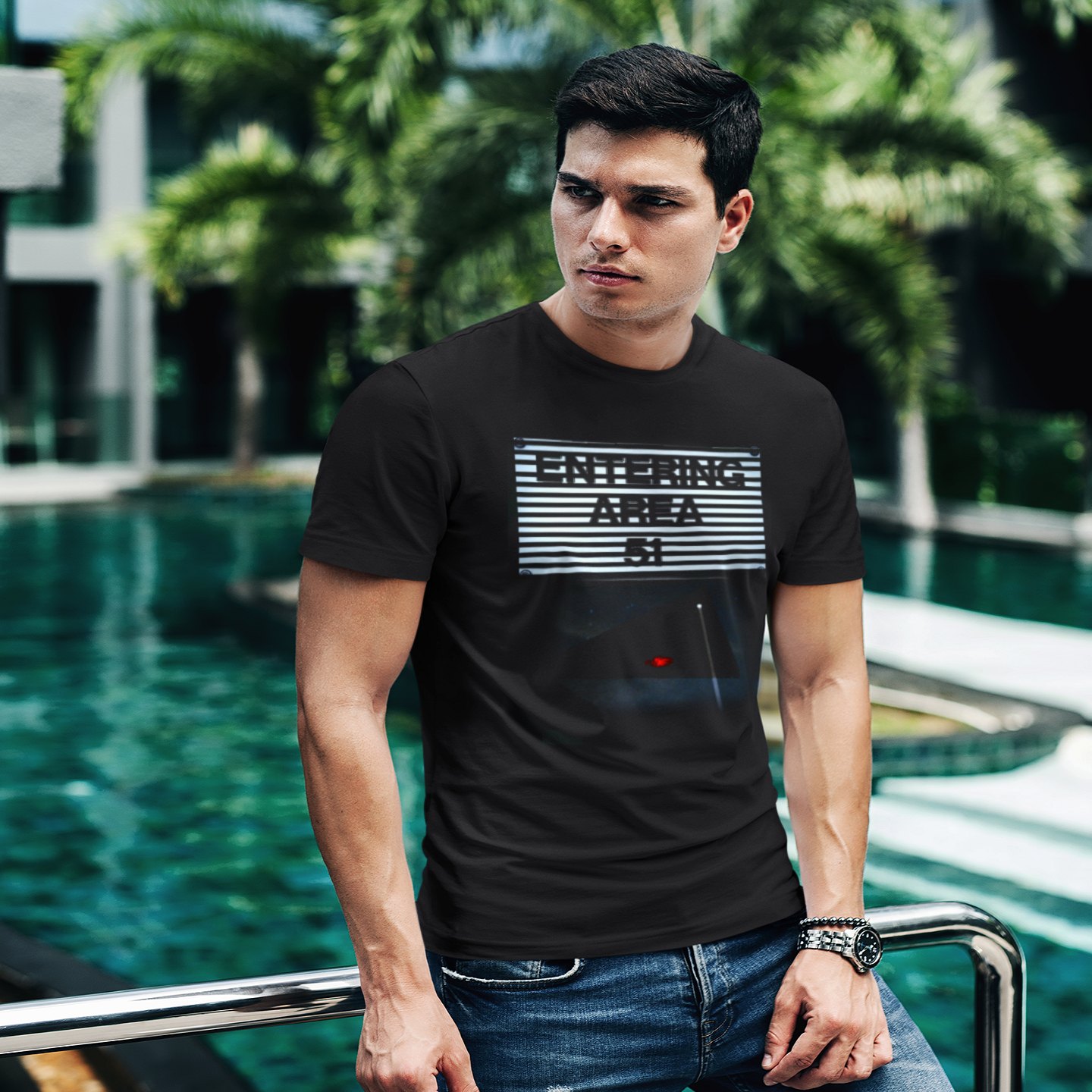 Area 51 – Black Triangle T-shirt in Black, front print, worn by a model (tropical pool, day). AI-edited photo: the real print artwork was digitally placed on a model photo.