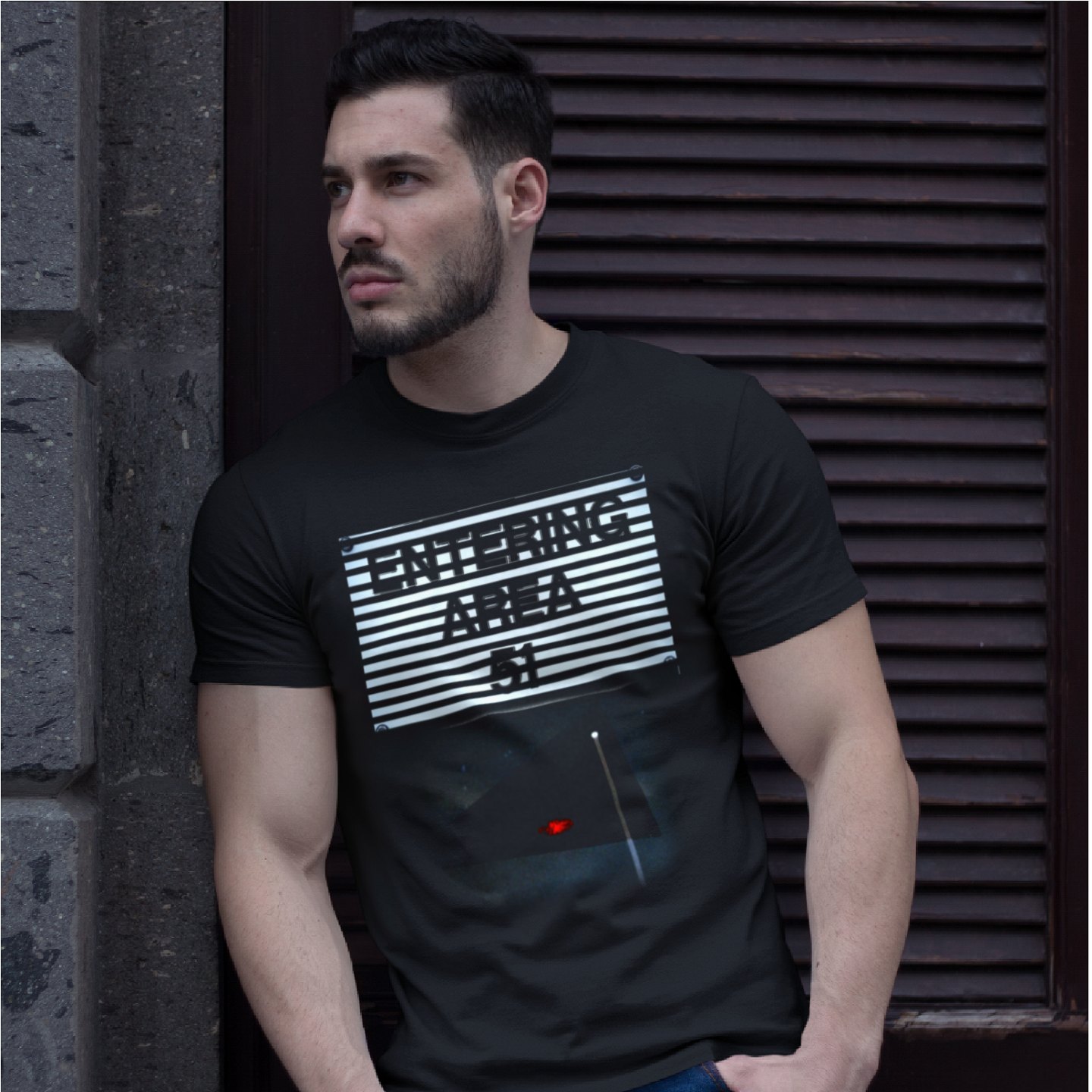 Area 51 – Black Triangle T-shirt in Black, front print, worn by a model (stone doorway, day). AI-edited photo: the real print artwork was digitally placed on a model photo.