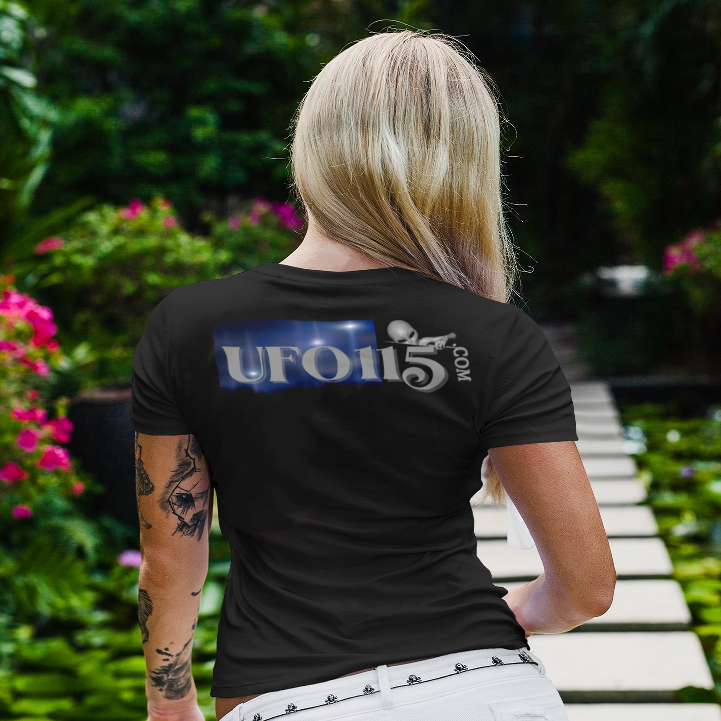 Area 51 – Black Triangle T-shirt in Black, back print, worn by a model (tropical garden walkway (back)). AI-edited photo: the real print artwork was digitally placed on a model photo.