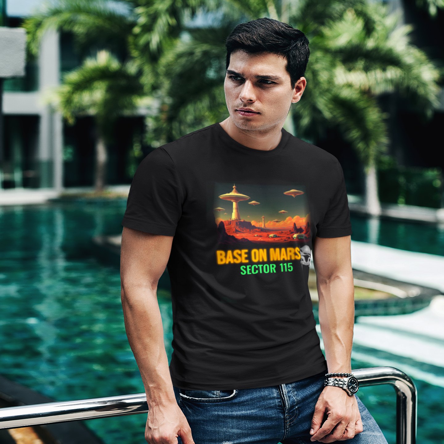 Base on Mars Retro T-shirt in Black, front print, worn by a model (tropical pool, day). AI-edited photo: the real print artwork was digitally placed on a model photo.