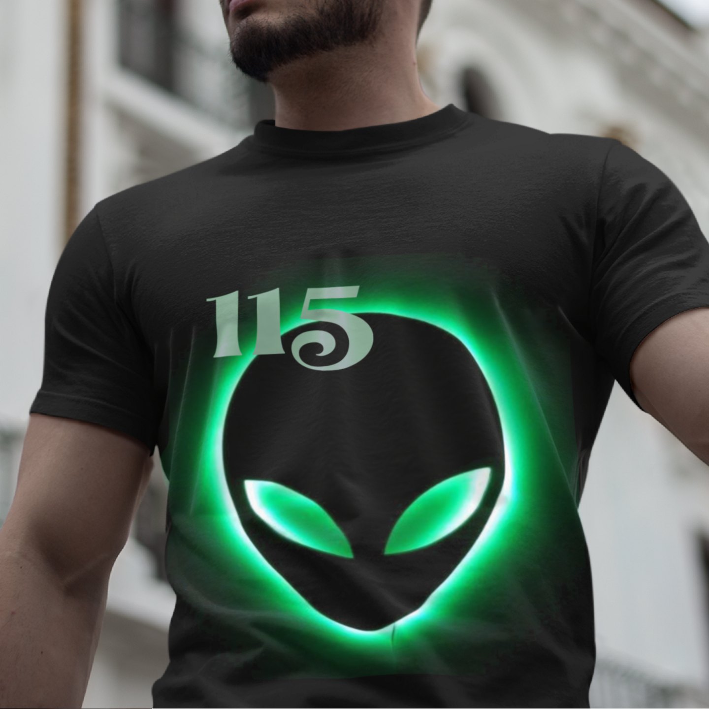Element 115 – Glowing Alien Grey T-shirt in Black, front print, worn by a model (classic architecture, day). AI-edited photo: the real print artwork was digitally placed on a model photo.