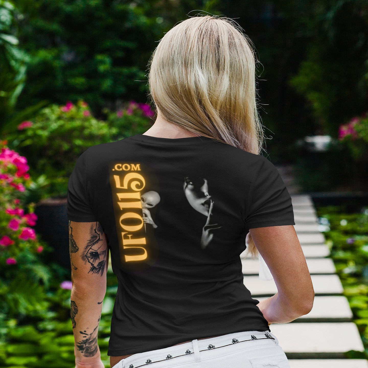 Element 115 – Uup You Never Saw Me T-shirt in Black, back print, worn by a model (tropical garden walkway (back)). AI-edited photo: the real print artwork was digitally placed on a model photo.