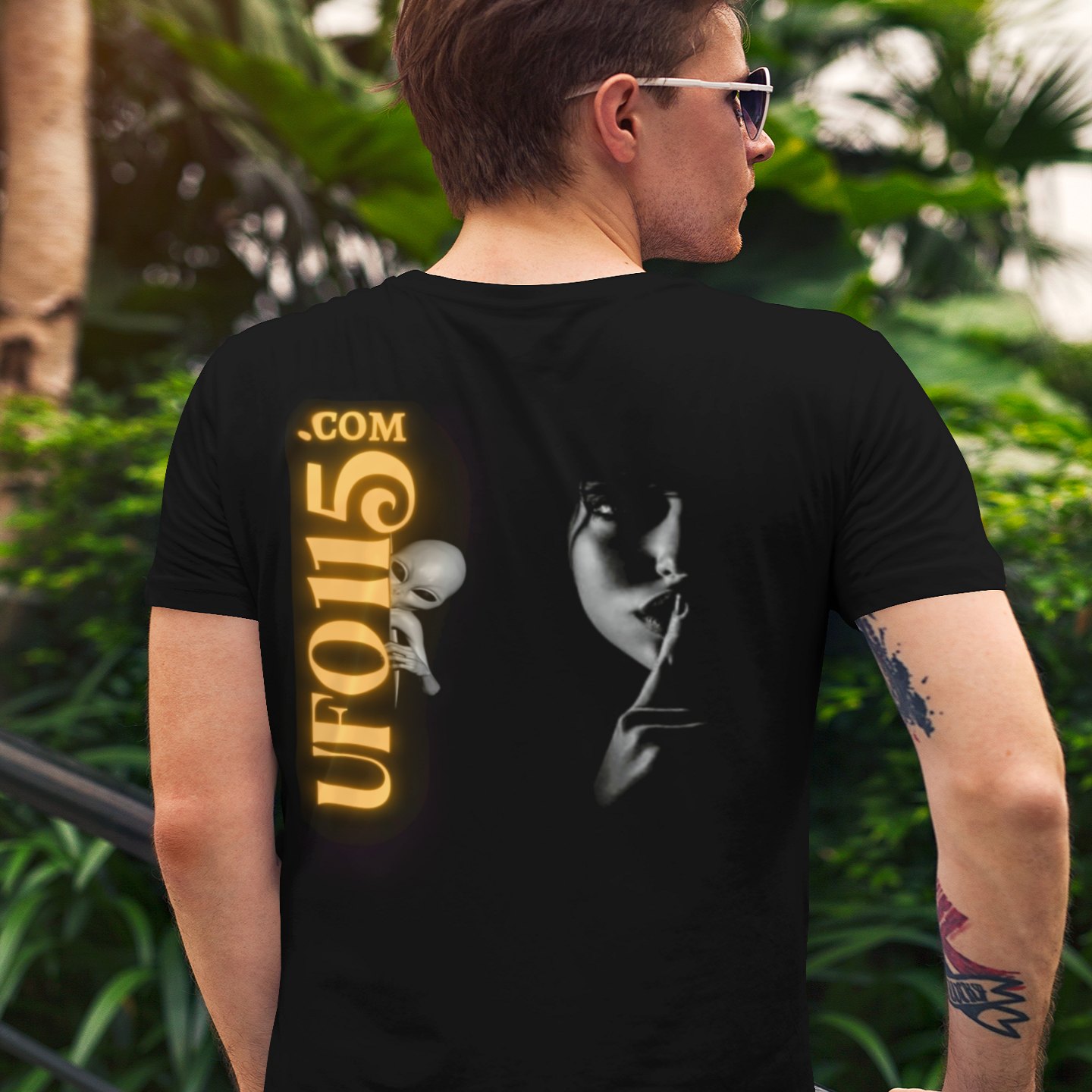 Lights Over the Desert 1997 T-shirt in Black, back print, worn by a model (tropical garden, day (back)). AI-edited photo: the real print artwork was digitally placed on a model photo.