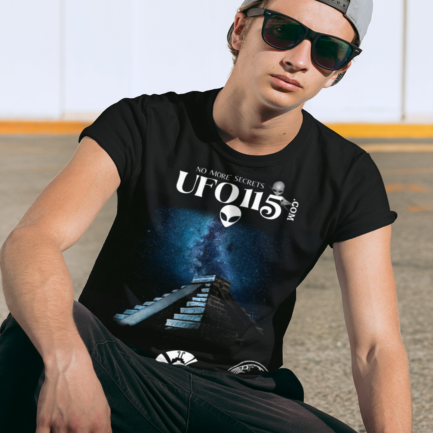 Mayan Pyramid Milky Way T-shirt in Black, front print, worn by a model (urban crouch, day). AI-edited photo: the real print artwork was digitally placed on a model photo.