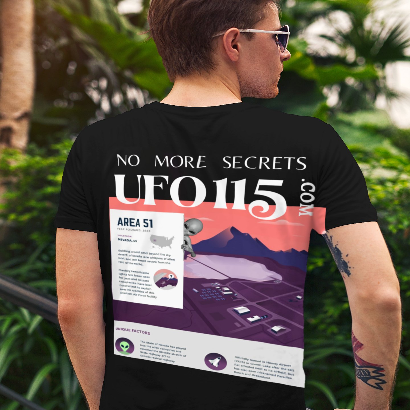 No More Secrets Area 51 T-shirt in Black, back print, worn by a model (tropical garden, day (back)). AI-edited photo: the real print artwork was digitally placed on a model photo.