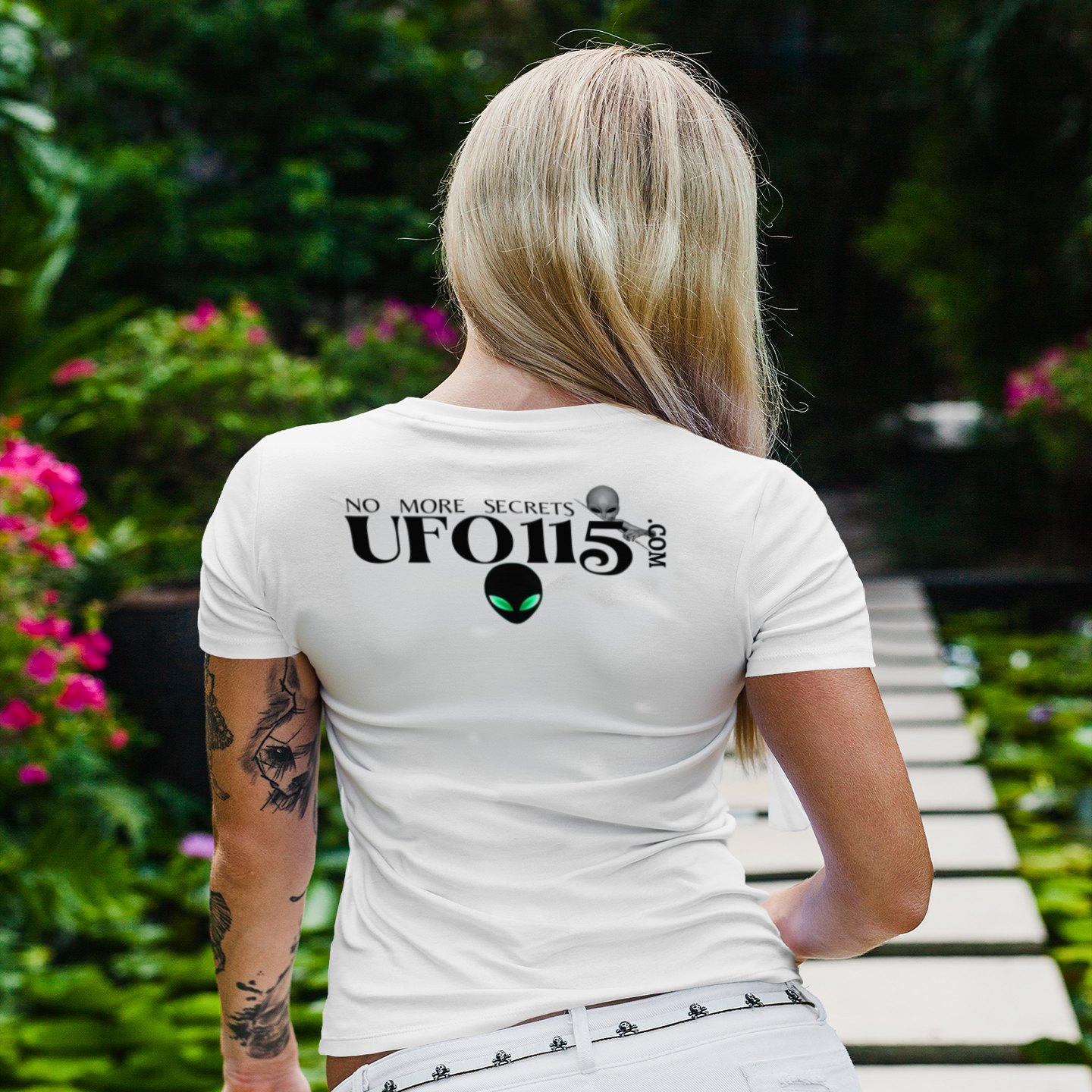 No More Secrets Green Eyes T-shirt in White, back print, worn by a model (tropical garden walkway (back)). AI-edited photo: the real print artwork was digitally placed on a model photo.