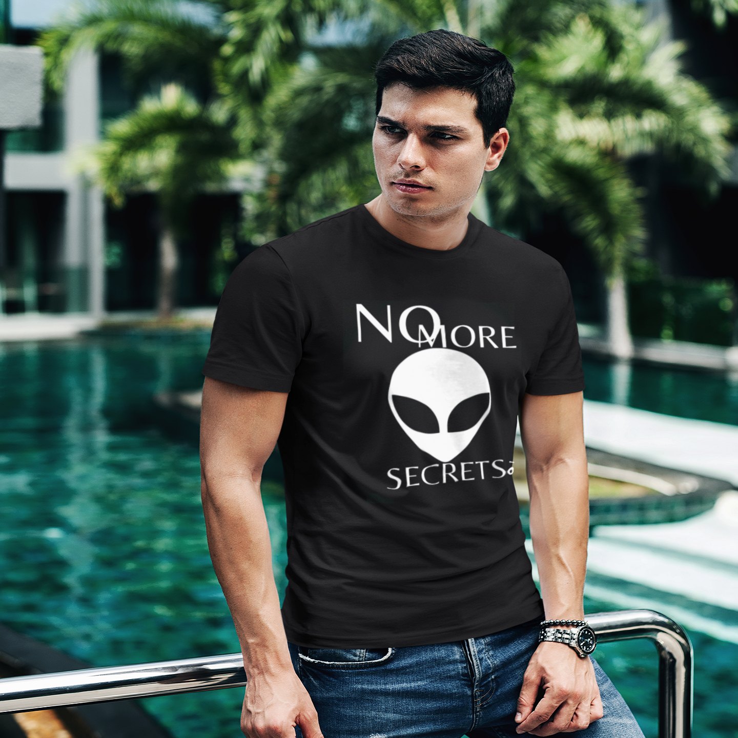 No More Secrets Kapustin Yar T-shirt in Black, front print, worn by a model (tropical pool, day). AI-edited photo: the real print artwork was digitally placed on a model photo.