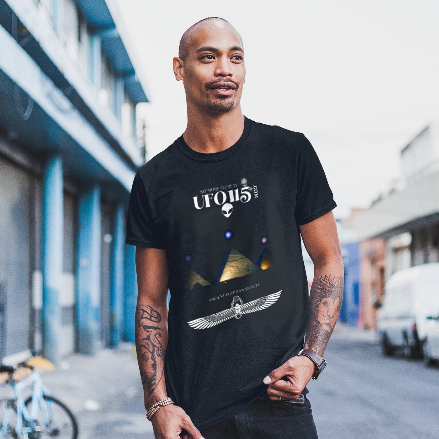 Orion's Belt Pyramids T-shirt in Black, front print, worn by a model (city street, day). AI-edited photo: the real print artwork was digitally placed on a model photo.