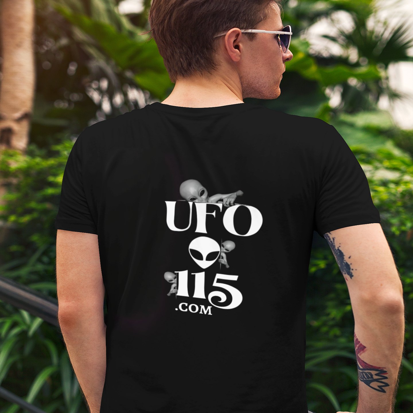 Sky Watcher Glowy Nights T-shirt in Black, back print, worn by a model (tropical garden, day (back)). AI-edited photo: the real print artwork was digitally placed on a model photo.