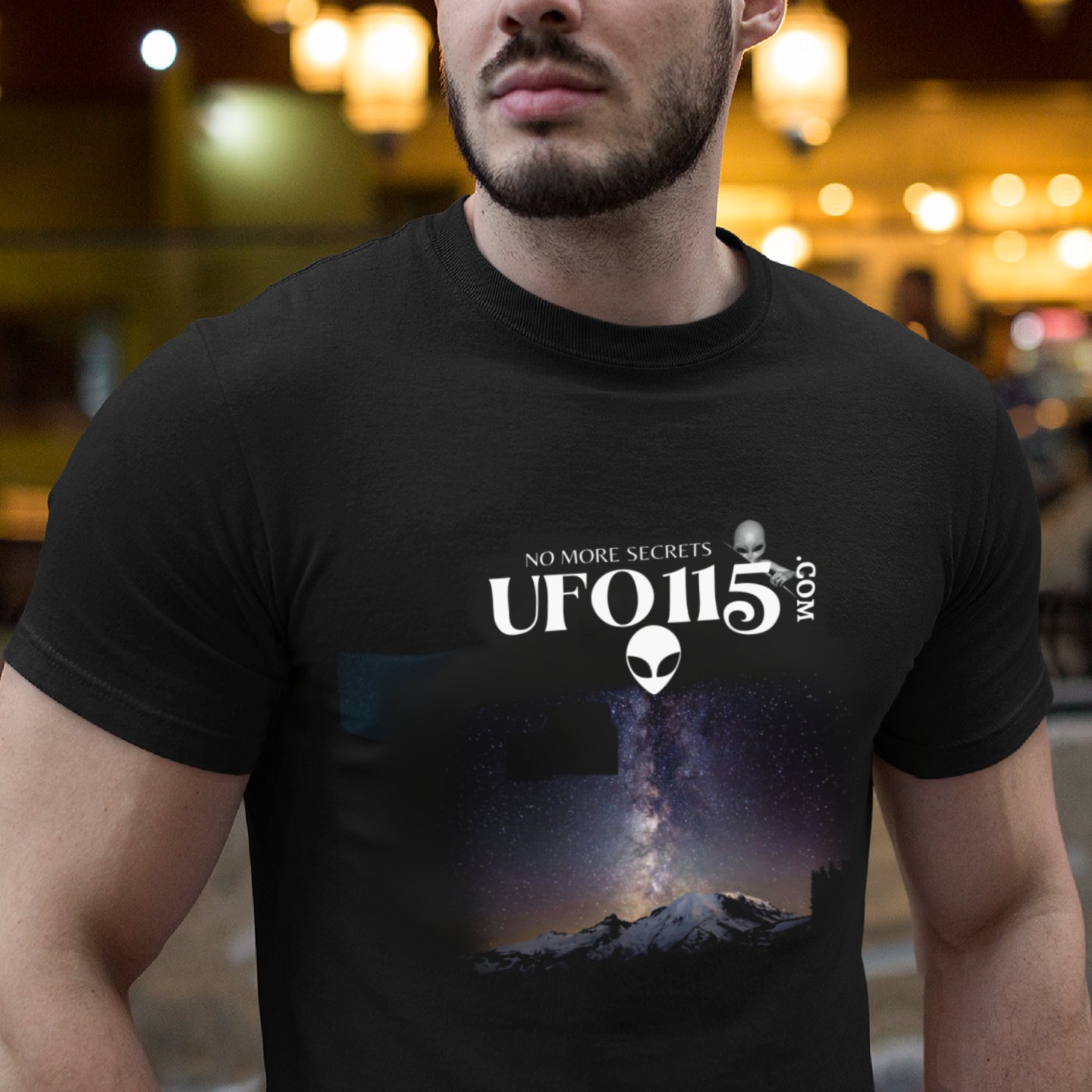 Sky Watcher Mountain Light T-shirt in Black, front print, worn by a model (bar lights, evening). AI-edited photo: the real print artwork was digitally placed on a model photo.