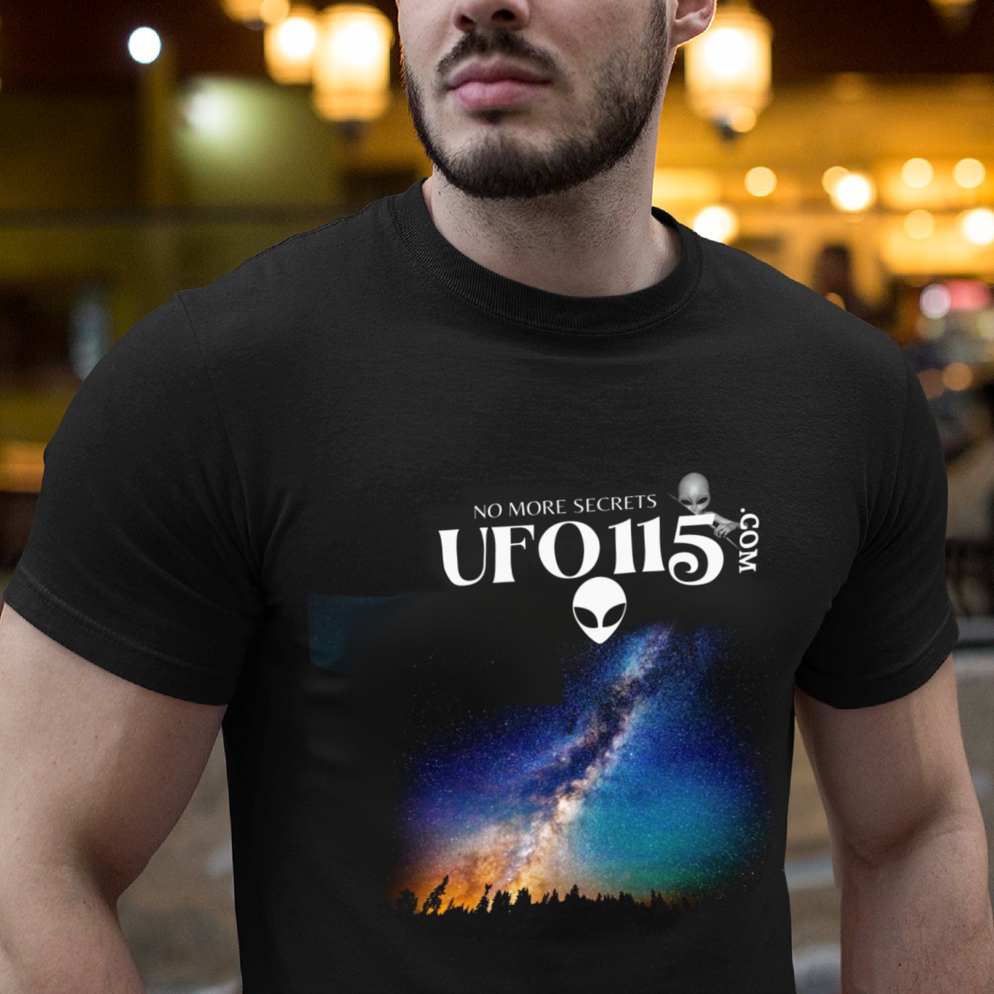 Sky Watcher Rainbow Bridge T-shirt in Black, front print, worn by a model (bar lights, evening). AI-edited photo: the real print artwork was digitally placed on a model photo.
