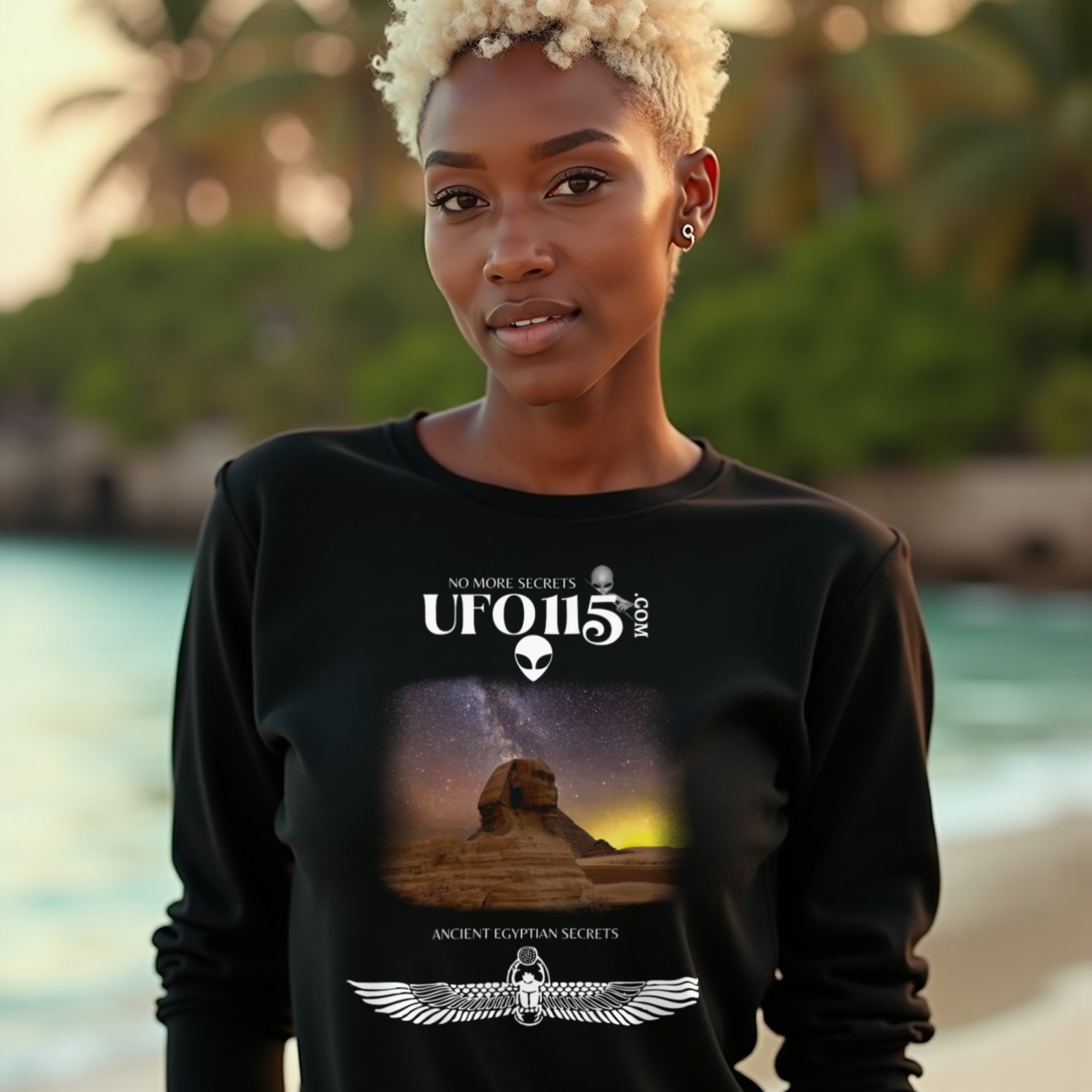 Sphinx and Sky long-sleeve T-shirt in Black, worn by a model (on a tropical beach at golden hour). AI-generated image: model and scene are AI-generated; the print is the real artwork.