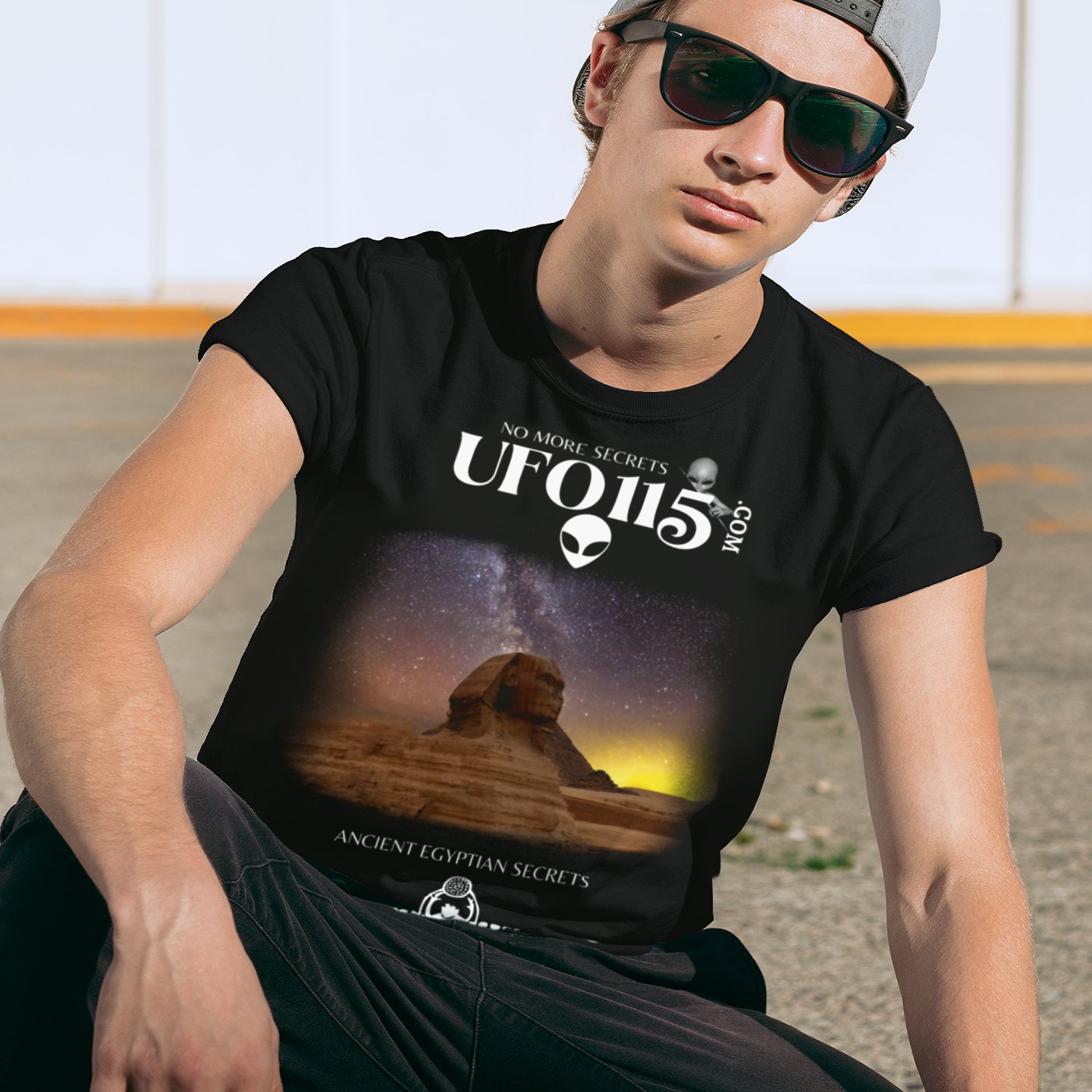 Sphinx and Sky T-shirt in Black, front print, worn by a model (urban crouch, day). AI-edited photo: the real print artwork was digitally placed on a model photo.