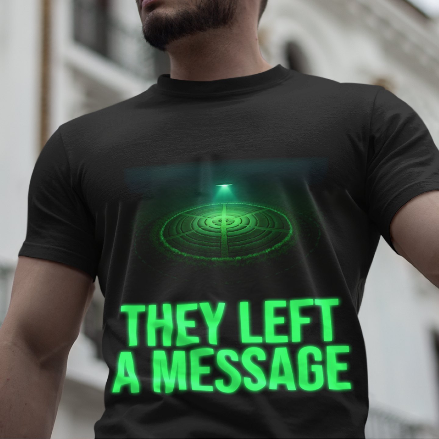 They Left a Message T-shirt in Black, front print, worn by a model (classic architecture, day). AI-edited photo: the real print artwork was digitally placed on a model photo.