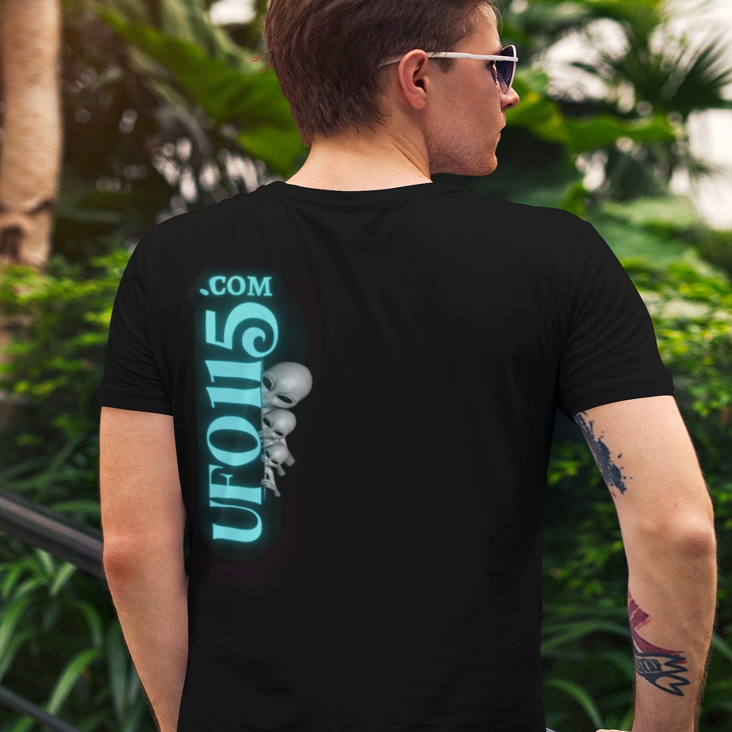 Truth Telling Bob T-shirt in Black, back print, worn by a model (tropical garden, day (back)). AI-edited photo: the real print artwork was digitally placed on a model photo.