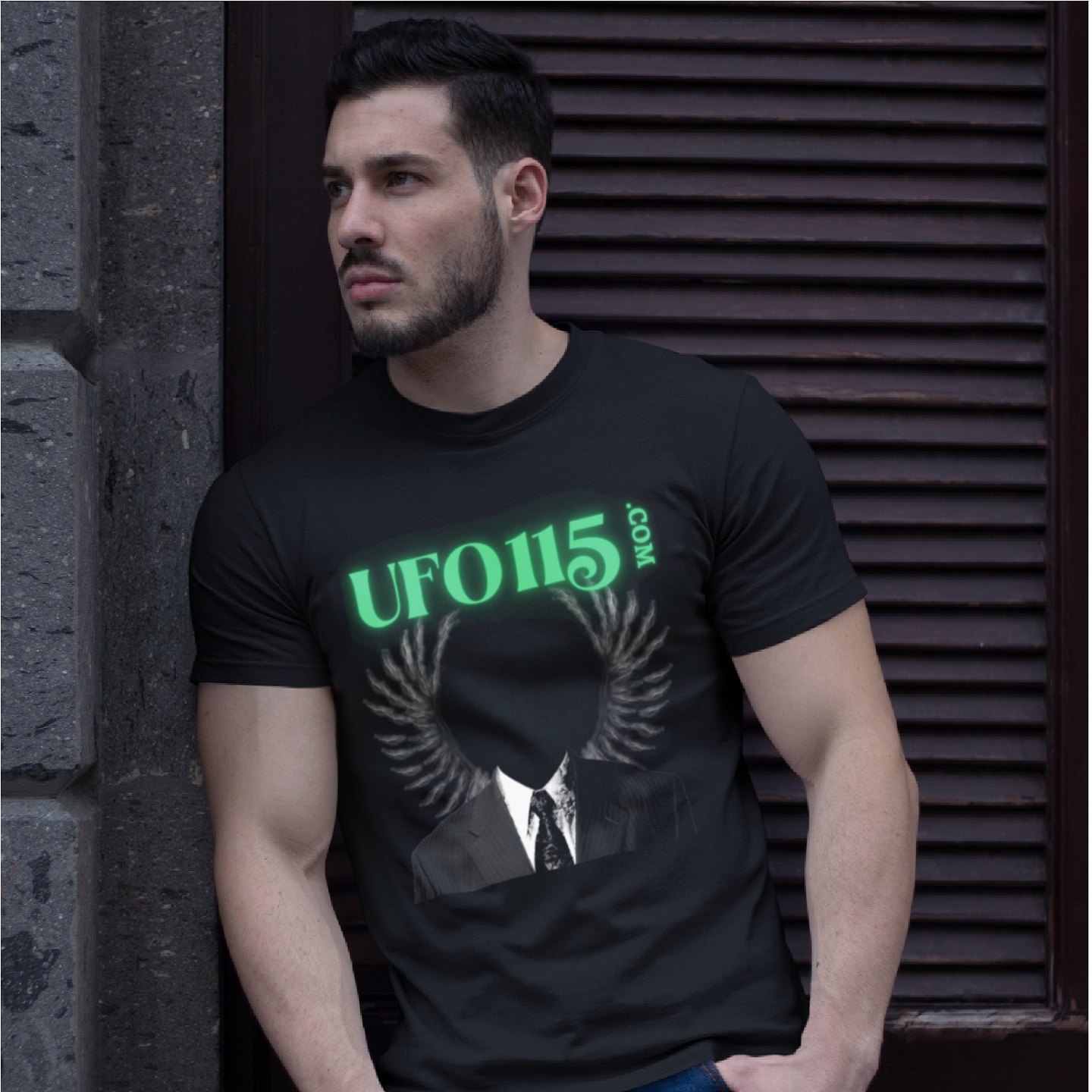 UFO115 – Green Angel T-shirt in Black, front print, worn by a model (stone doorway, day). AI-edited photo: the real print artwork was digitally placed on a model photo.