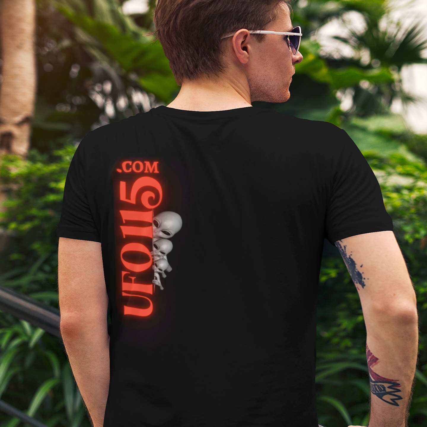 UFO115 Red Angel T-shirt in Black, back print, worn by a model (tropical garden, day (back)). AI-edited photo: the real print artwork was digitally placed on a model photo.