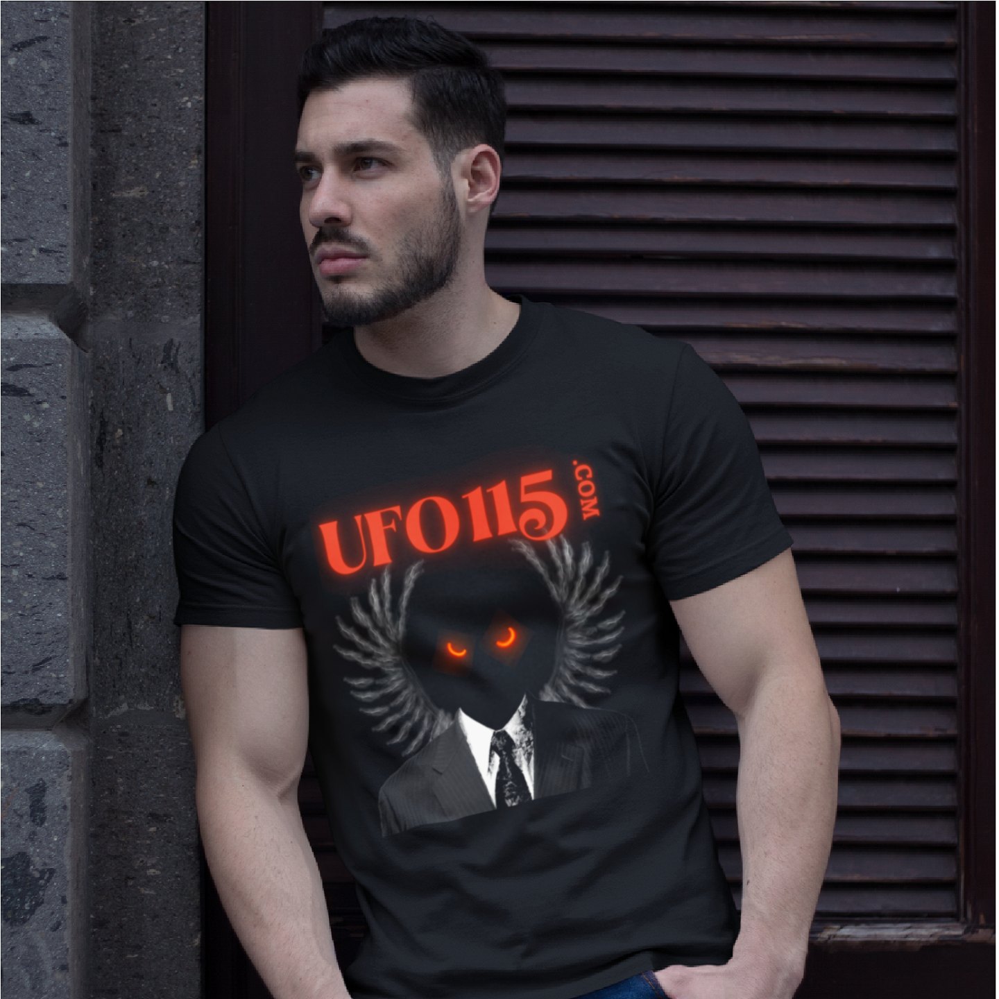 UFO115 Red Angel T-shirt in Black, front print, worn by a model (stone doorway, day). AI-edited photo: the real print artwork was digitally placed on a model photo.