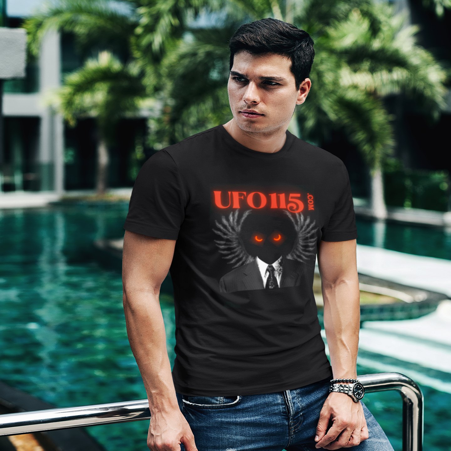UFO115 Red Angel T-shirt in Black, front print, worn by a model (tropical pool, day). AI-edited photo: the real print artwork was digitally placed on a model photo.